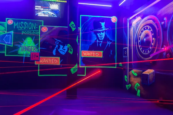 Laserraum mit Wanted-Plakaten und Weltkarte, rote Strahlen quer durch den Raum, oben ein Monitor