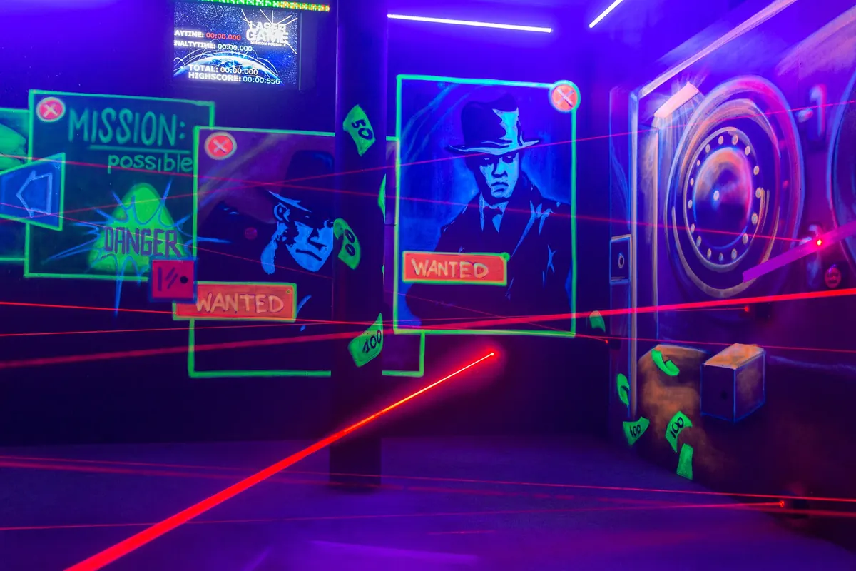 Laserraum mit Wanted-Plakaten und Weltkarte, rote Laserstrahlen ziehen sich diagonal durch den Raum