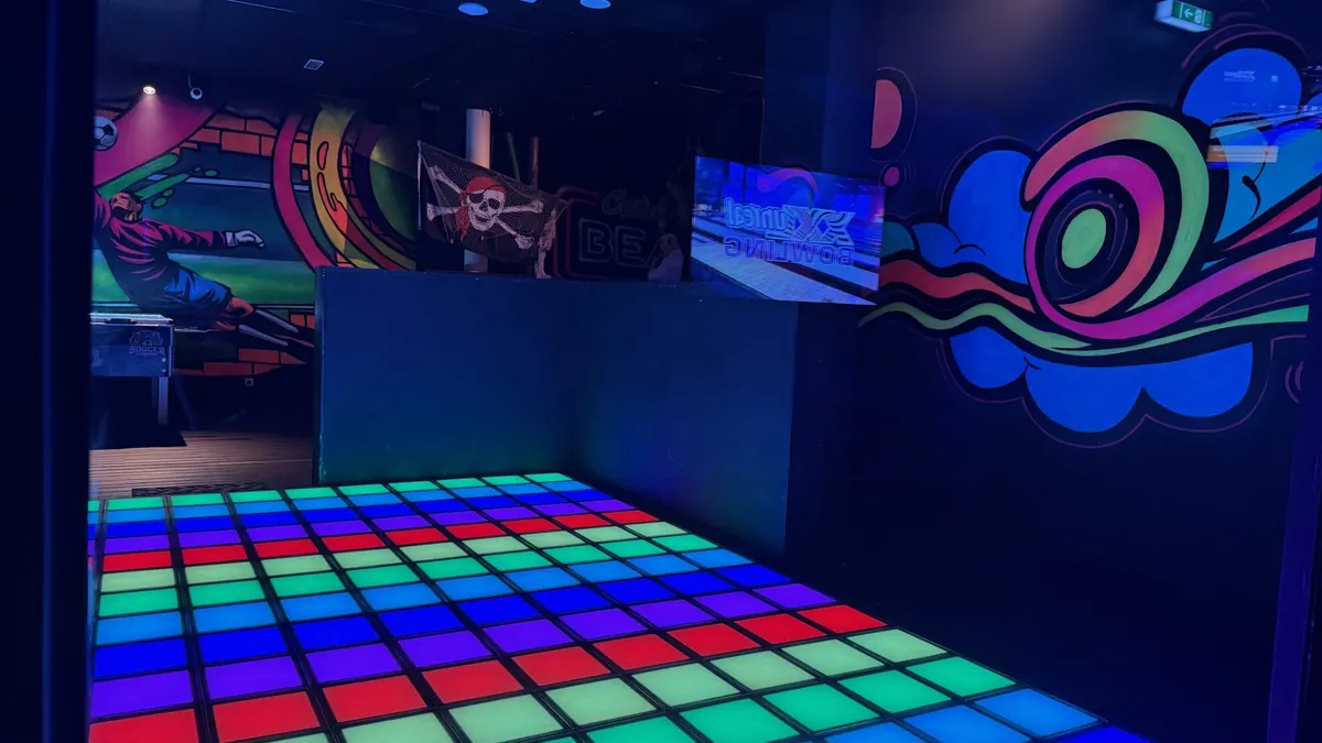 Light Jumper von oben: Raster aus roten, grünen und blauen LED-Feldern vor bunt bemalten Wänden